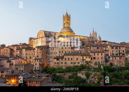 Kathedrale von Siena bei Sonnenaufgang, gotischer Architekturstil, vor ihr Häuser der Altstadt, Siena, Toskana, Italien Stockfoto