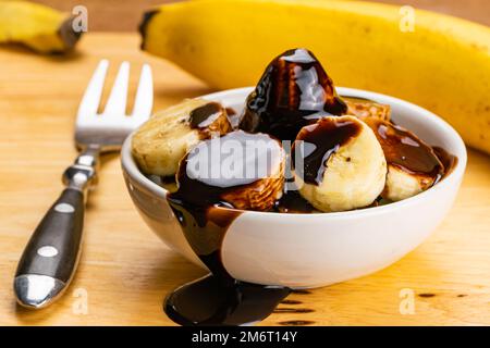 Blick auf geschnittene, geschälte, reife Bio-Bananen mit Schokoladensirup. Stockfoto