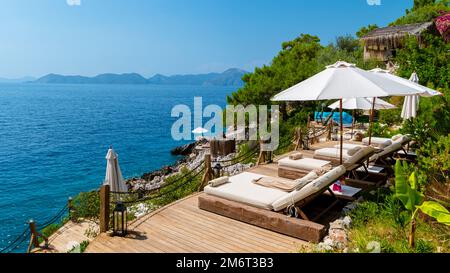 Strandliegen mit weißen Sonnenschirmen mit Blick auf das Meer in der Türkei Stockfoto