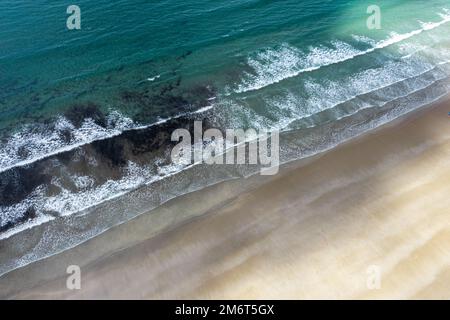 Blick von oben auf die Drohne auf das türkisfarbene Meer und die weißen Wellen, die an einem goldenen Sandstrand brechen Stockfoto