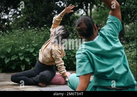 Melissa Aguirre, ganzheitliche Life Coach und Stress Management Specialist, Left, leitet die USA Army Captain Lesley Tarongoy, Krankenschwester in der Notaufnahme, durch eine Yoga-Routine im Freedom Park am Brooke Medical Center, San Antonio, Texas, 4. Mai 2022. Tarongoy nahm an Aguirres Yoga-Kursen Teil, um Achtsamkeit zu dekomprimieren und zu üben, nachdem sie 2020 einen besonders stressigen Einsatz in Afghanistan beschrieben hatte. Stockfoto