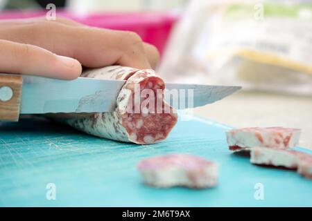 Der Hand, die Fuet mit dem Messer zerkleinert Stockfoto