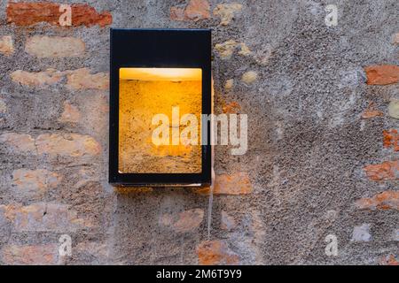 Alte Fassadenbeleuchtung. Schwarze quadratische Lampe an Grunge-Backsteinwand. Moderne Straßenbeleuchtung. Nahaufnahme Stockfoto