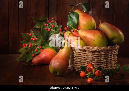 Reife Birnen in einem Korb auf dunklem Holzhintergrund in rustikalem Stil Stockfoto