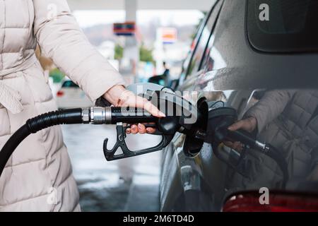 Frau, die an der Tankstelle Benzin im Auto pumpt. Konzept der Preiserhöhung bei Benzin oder Benzin. Stockfoto