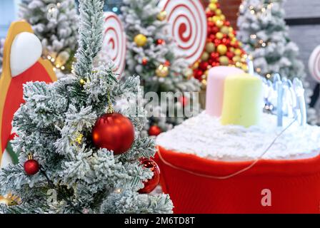 Schneebedeckter Weihnachtsbaum mit roten matten und glänzenden Weihnachtsbällen. Stockfoto