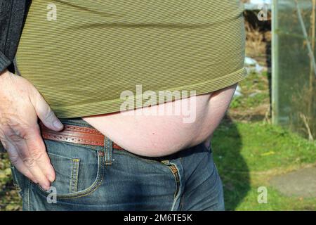 Übergewichtiger Bauch. Der große, fette Magen des Mannes ragt über seine Hose. Stockfoto