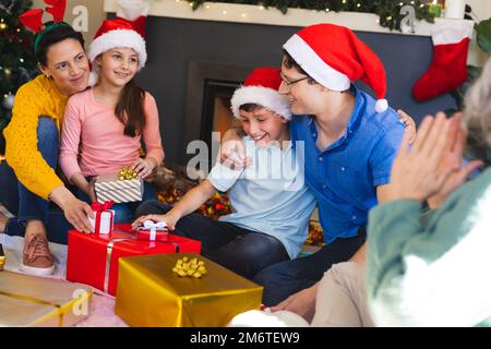 Die kaukasische Familie verbringt Zeit miteinander und packt weihnachtsgeschenke aus Stockfoto