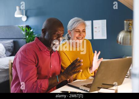 Ein vielseitiges Senior-Paar, das am Tisch sitzt und arbeitet Stockfoto