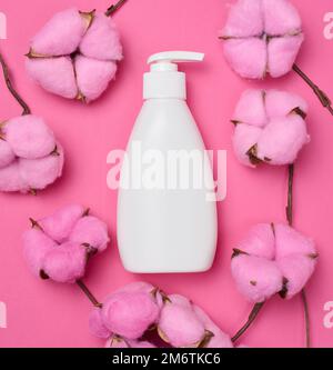Weiße Kunststoffflasche mit Pumpe auf pinkfarbenem Hintergrund. Stockfoto