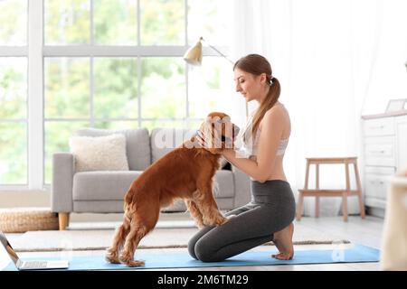 Sportliche junge Frau mit rotem Cockerspaniel zu Hause Stockfoto