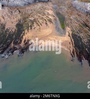 Blick von oben auf eine felsige Bucht mit Sandstrand und türkisfarbenem Ozeanwasser Stockfoto