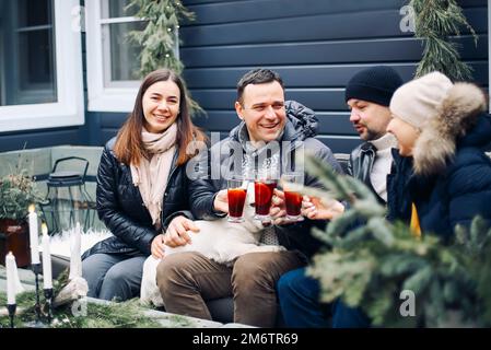 Lagerfeuer-Party. Fröhliches junges Familienpaar, das sich im Winter am Lagerfeuer mit Freunden trifft Stockfoto