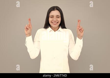 Porträt einer lustigen Frau mit gekreuzten Daumen für viel Glück, isolierter Hintergrund. Kopfschuss einer frohen Frau kreuzt die Finger mit positivem Ausdruck Stockfoto