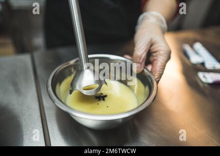 Nahaufnahme eines Konditors, der mit einem Stabmixer Gärung und Lebensmittelfarbe mischt. Hochwinkelschuss. Hochwertiges Foto Stockfoto
