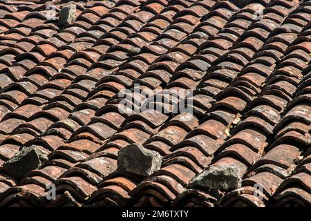 Dach des alten Landhauses von verwitterten alten Tonziegeln Nahaufnahme Stockfoto