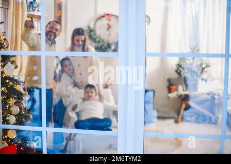 Kleine Kinder helfen Eltern beim Dekorieren des Weihnachtsbaums und bereiten das Haus für Weihnachten und Neujahr vor. Stockfoto