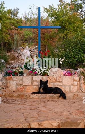 Das Blaue Kreuz und ein freizügiger Hund in Medjugorje. Ein freitragender Hund ist ein gewöhnlicher Anblick. Stockfoto