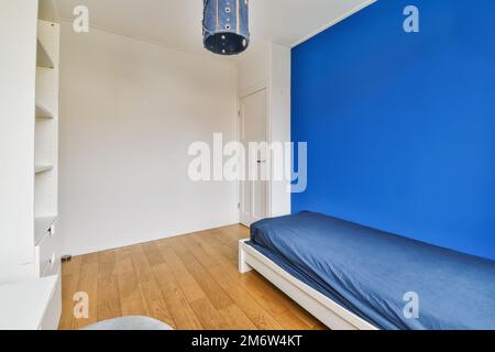 Ein Schlafzimmer mit blauen Wänden und Holzfußboden, inklusive einem Einzelbett in der Ecke des Zimmers auf der linken Seite ist ein Stockfoto