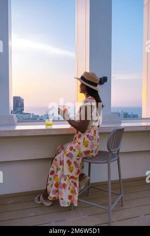 Junge Frauen, die einen Drink auf einer Dachbar trinken Stockfoto