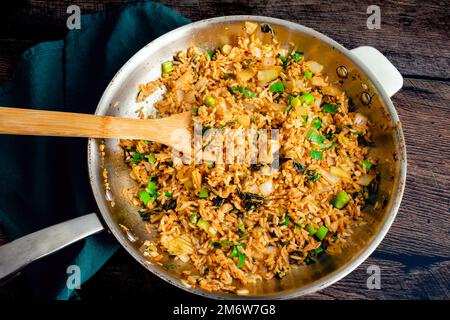 Kimchi gebratener Reis in einer großen Pfanne mit einem Bambusspatel: Blick von oben auf eine große Pfanne Kimchi Bokkeumbap Stockfoto