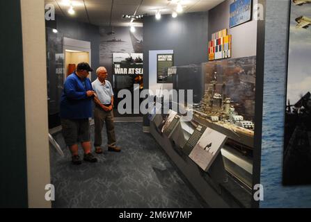 Gary Royse (rechts), Freiwilliger Dozent im Hampton Roads Naval Museum, stellt am Freitag, den 6. Mai 2022, Fragen von einem Besucher seiner Galerie. Das Museum befindet sich im zweiten Stock des Nauticus Campus in Downtown Norfolk, Virginia, und beherbergt ein robustes Freiwilligenkorps, das Besuchern hilft, die Geschichte der Marine in der Gegend um Hampton Roads, Virginia, kennenzulernen. Stockfoto