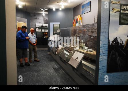 Gary Royse (rechts), Freiwilliger Dozent im Hampton Roads Naval Museum, stellt am Freitag, den 6. Mai 2022, Fragen von einem Besucher seiner Galerie. Das Museum befindet sich im zweiten Stock des Nauticus Campus in Downtown Norfolk, Virginia, und beherbergt ein robustes Freiwilligenkorps, das Besuchern hilft, die Geschichte der Marine in der Gegend um Hampton Roads, Virginia, kennenzulernen. Stockfoto