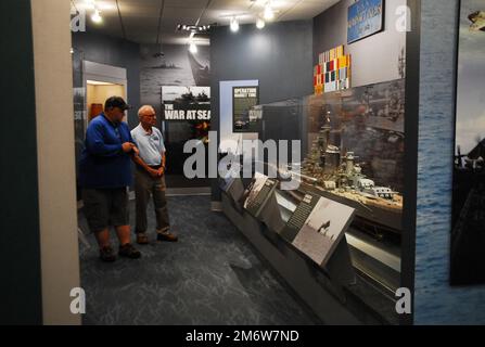 Gary Royse (rechts), Freiwilliger Dozent im Hampton Roads Naval Museum, stellt am Freitag, den 6. Mai 2022, Fragen von einem Besucher seiner Galerie. Das Museum befindet sich im zweiten Stock des Nauticus Campus in Downtown Norfolk, Virginia, und beherbergt ein robustes Freiwilligenkorps, das Besuchern hilft, die Geschichte der Marine in der Gegend um Hampton Roads, Virginia, kennenzulernen. Stockfoto