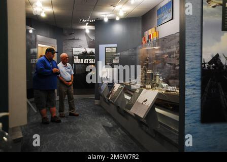 Gary Royse (rechts), Freiwilliger Dozent im Hampton Roads Naval Museum, stellt am Freitag, den 6. Mai 2022, Fragen von einem Besucher seiner Galerie. Das Museum befindet sich im zweiten Stock des Nauticus Campus in Downtown Norfolk, Virginia, und beherbergt ein robustes Freiwilligenkorps, das Besuchern hilft, die Geschichte der Marine in der Gegend um Hampton Roads, Virginia, kennenzulernen. Stockfoto