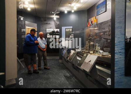 Gary Royse (rechts), Freiwilliger Dozent im Hampton Roads Naval Museum, stellt am Freitag, den 6. Mai 2022, Fragen von einem Besucher seiner Galerie. Das Museum befindet sich im zweiten Stock des Nauticus Campus in Downtown Norfolk, Virginia, und beherbergt ein robustes Freiwilligenkorps, das Besuchern hilft, die Geschichte der Marine in der Gegend um Hampton Roads, Virginia, kennenzulernen. Stockfoto