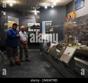 Gary Royse (rechts), Freiwilliger Dozent im Hampton Roads Naval Museum, stellt am Freitag, den 6. Mai 2022, Fragen von einem Besucher seiner Galerie. Das Museum befindet sich im zweiten Stock des Nauticus Campus in Downtown Norfolk, Virginia, und beherbergt ein robustes Freiwilligenkorps, das Besuchern hilft, die Geschichte der Marine in der Gegend um Hampton Roads, Virginia, kennenzulernen. Stockfoto