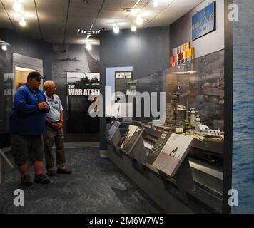 Gary Royse (rechts), Freiwilliger Dozent im Hampton Roads Naval Museum, stellt am Freitag, den 6. Mai 2022, Fragen von einem Besucher seiner Galerie. Das Museum befindet sich im zweiten Stock des Nauticus Campus in Downtown Norfolk, Virginia, und beherbergt ein robustes Freiwilligenkorps, das Besuchern hilft, die Geschichte der Marine in der Gegend um Hampton Roads, Virginia, kennenzulernen. Stockfoto