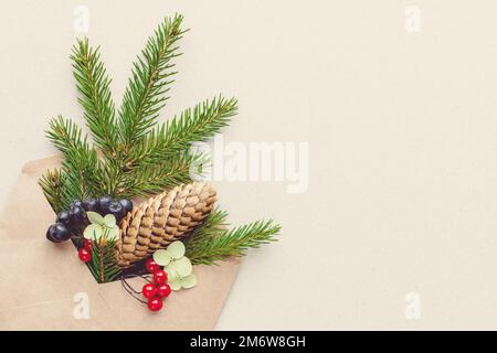 Weihnachtsdekoration, Tannenzweig in Umschlag auf Kraftpapier-Hintergrund, Kopierraum Stockfoto