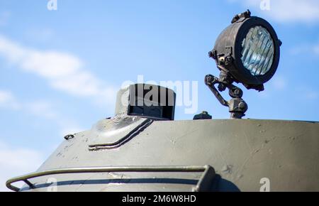 Frontscheinwerfer eines sowjetischen Panzers. Sehr heller Sucher auf dem Panzerturm, Nahaufnahme. Gepanzertes Infanterie-Kampffahrzeug Stockfoto