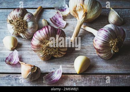 Knoblauchzwiebeln und Nelken auf Holztischhintergrund Stockfoto