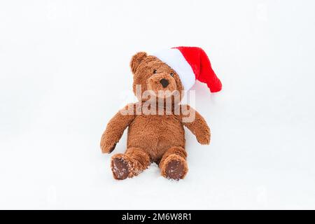 Teddybär im Weihnachtsmütze im Schnee sitzend, Platz kopieren Stockfoto