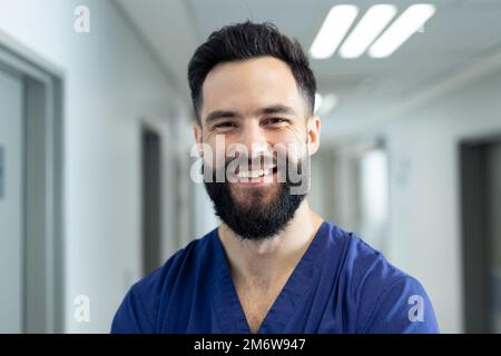 Portrait von lächelndem, bärtigen, weißer, männlicher Gesundheitsarbeiter im Krankenhausflur, Kopierraum Stockfoto