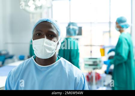 Porträt eines afroamerikanischen männlichen Chirurgen mit Gesichtsmaske im Operationssaal, mit Kopierraum Stockfoto