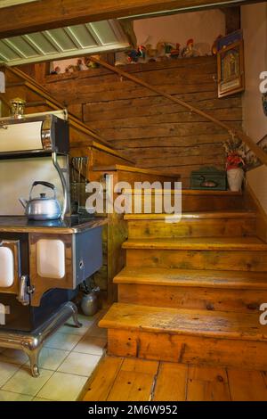 1850er Jahre Sweet Heart Retro Modell Koch Herd handgefertigt von Elmira Herd arbeitet in Küche mit alten Kiefernholztreppe in 1980 rekonstruiertem Blockhaus. Stockfoto