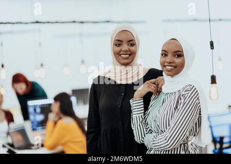 Porträt von zwei afroamerikanischen Geschäftsfrauen, die miteinander reden, während sie in einem modernen Büro mit ihrer colle stehen Stockfoto