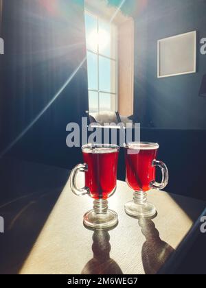 Zwei Gläser Glühwein auf dem Fensterbrett mit Blick auf die Winterberge Stockfoto