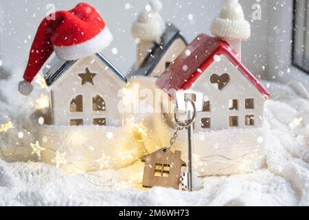 Schlüssel zum Haus mit Schlüsselanhänger auf einem gemütlichen Zuhause mit Weihnachtsdekor. Ein Geschenk für Neujahr, Christm Stockfoto