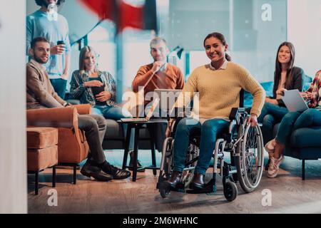 Geschäftsfrau im Rollstuhl, die ein Geschäftstreffen mit dem Team in einem modernen Büro führt. Eine Gruppe junger Freiberufler vereinbart online neue Stockfoto