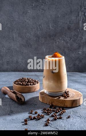 Eiskaffee in einem großen Glas mit Sahne und Kaffeebohnen. Kaltes Kaffeegetränk auf dunklem Hintergrund mit Kopierbereich. Stockfoto