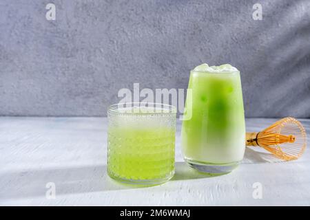 Matcha-Tee. Latte mit grünem Eistee im Glas. Ausgepeitschter Grean-Tee mit Milch. Gesundes veganisches Getränk, aus der Nähe. Stockfoto