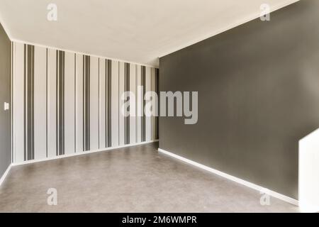 Ein leerer Raum mit schwarz-weiß gestreiften Tapeten an den Wänden und eine Tür in der Ecke Stockfoto