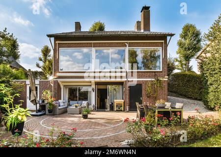 Ein Haus in den niederlanden mit Außenterrasse und gepflasterten Mauern, umgeben von üppig grünen Bäumen Stockfoto