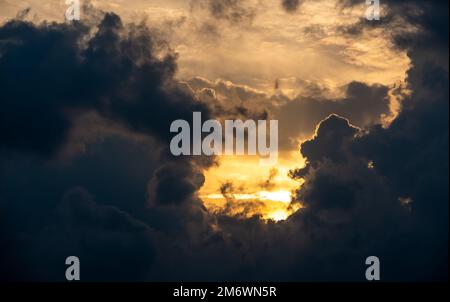 Sonne hinter dunklen Wolken. Dramatischer Sonnenreis im Winter. Stürmische Wolken Stockfoto