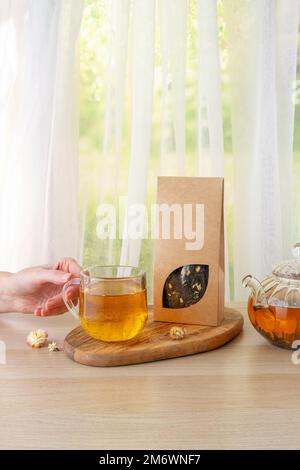Bio-Teemarkierung und Verpackungsmodell. Grüner Jasmintee in Glas Teekanne auf dem Tisch. Heißer Tee ist in den Glasbechern. Teekanne und Stockfoto