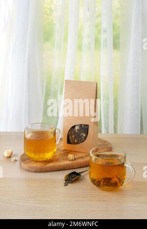 Bio-Teemarkierung und Verpackungsmodell. Grüner Jasmintee in Glas Teekanne auf dem Tisch. Heißer Tee ist in den Glasbechern. Teekanne und Stockfoto